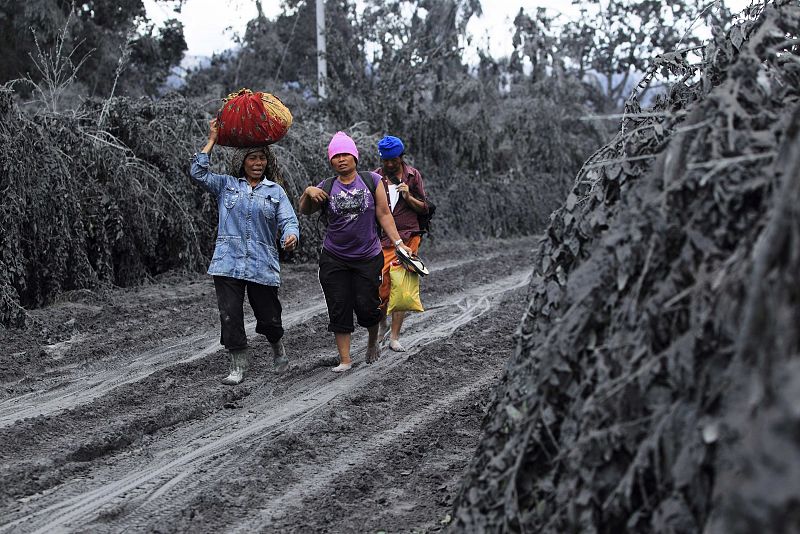 Villagers walk through mud and ash as they evacuate after Mount Sinabung erupted in Karo district