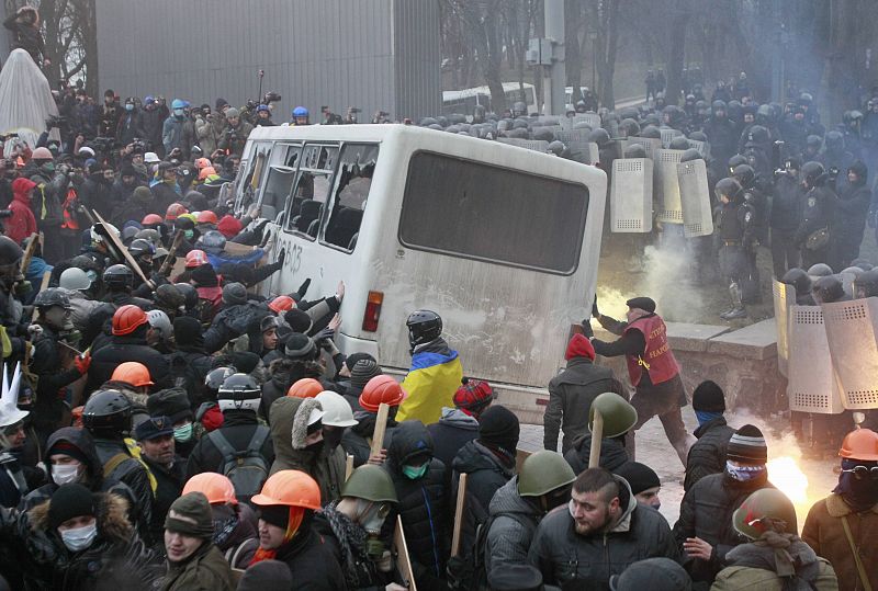 Pro-European integration protesters attack a police van during a rally near government administration buildings in Kiev