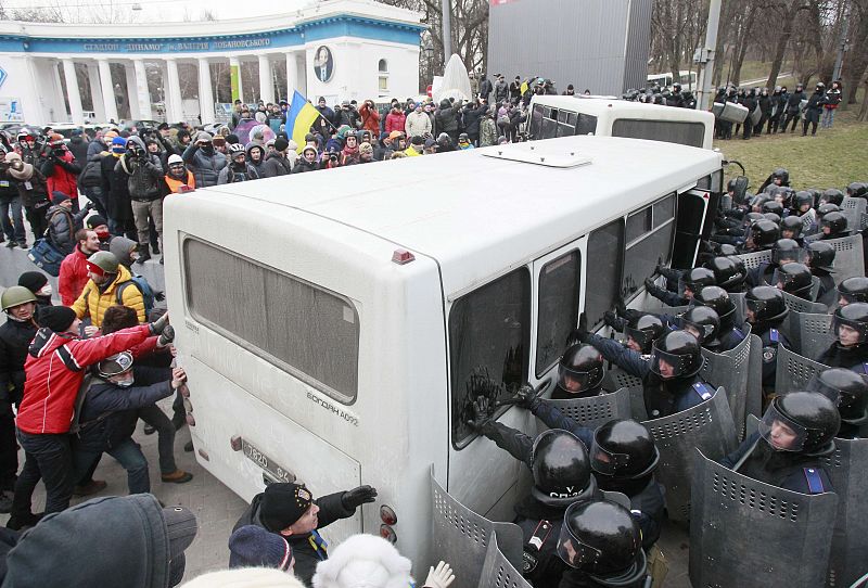 Pro-European protesters attempt to roll a police van over during a rally near government administration buildings in Kiev