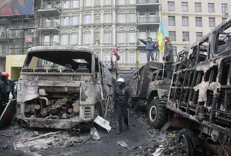 Manifestantes junto a vehículos calcinados en la capital ucraniana