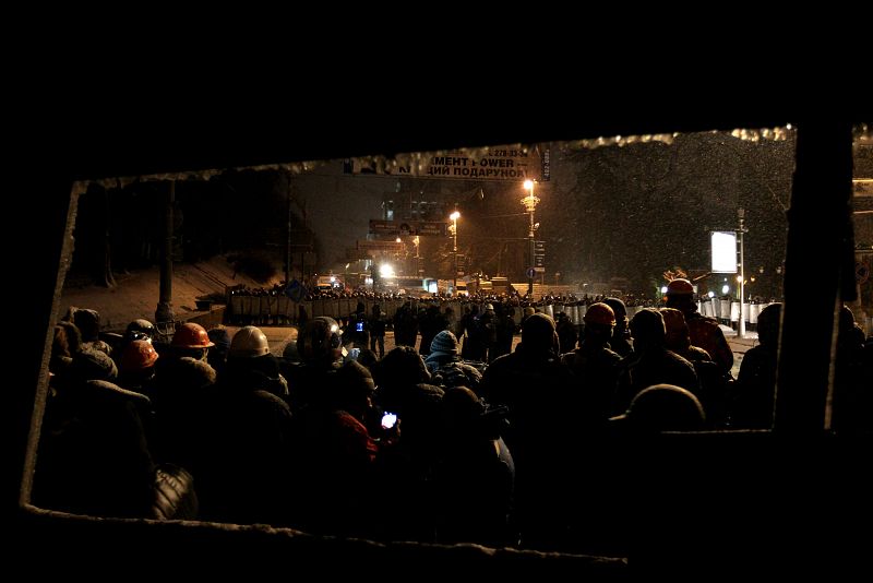 Manifestantes se parapetan tras un vehículo quemado