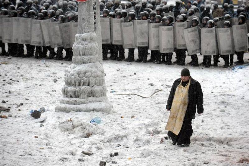 Un sacerdote intenta mediar entre policía y manifestantes. 