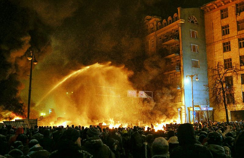 Policías antimotines intentan apagar el fuego durante la protesta en el centro de Kiev