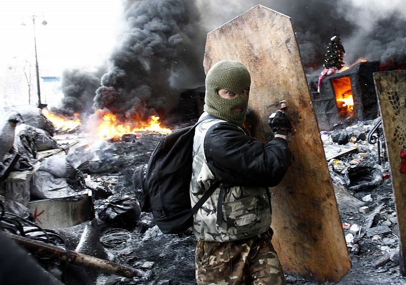 Un manifestante anti-gubernamental se cubre tras una barricada en Kiev