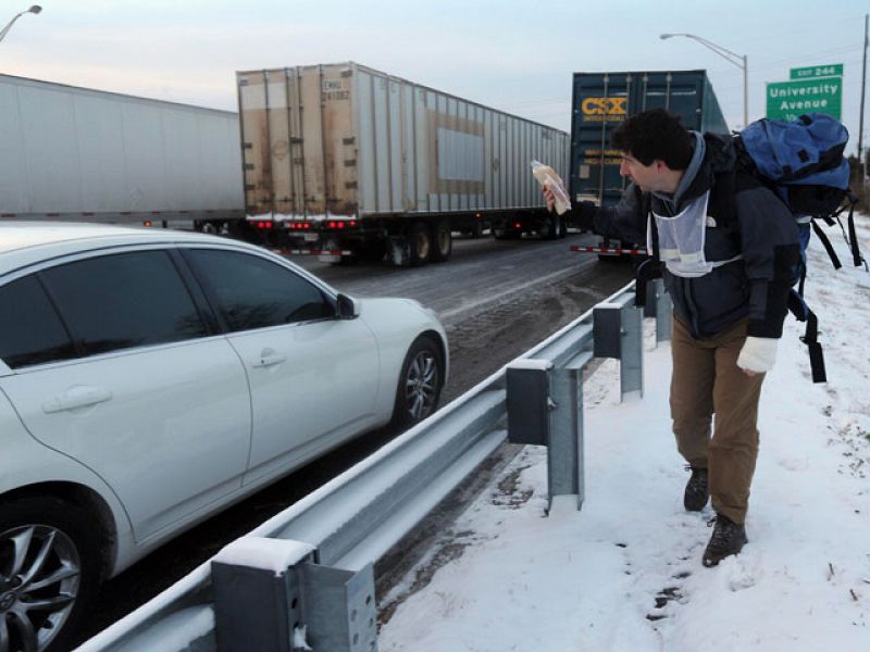 Un hombre camina en la autopista ofreciendo bebida caliente a los conductores atrapados.