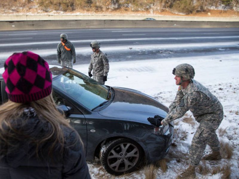El ejército ayuda a una mujer a sacar su coche atrapado en la nieve.