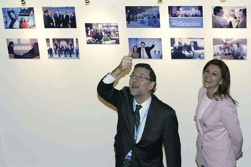 Rajoy y Cospedal observan algunas fotografías de una exposición durante la Convención Nacional del PP.