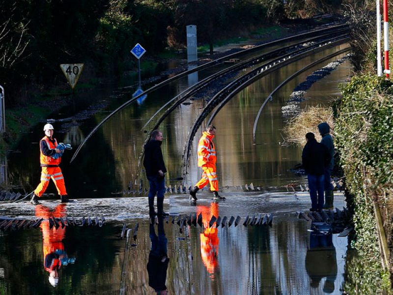 Trabajadores ferroviarios cruzan las vías inundadas por el Támesis en las cercanías de Datchet, al sur de Inglaterra.