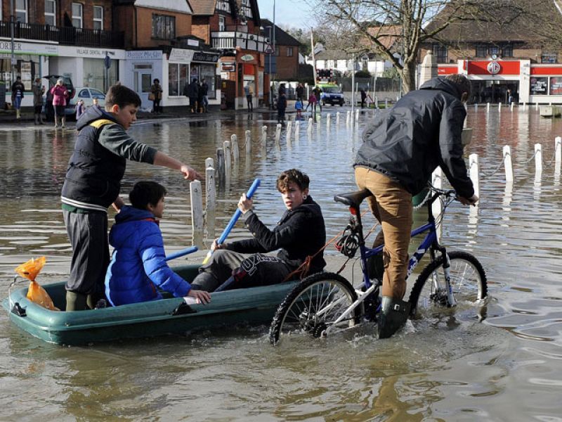 Un grupo de jóvenes avanza por una calle inundada de Berkshire. El nivel de las aguas del río Támesis está en su nivel más alto desde los pasados años ochenta.