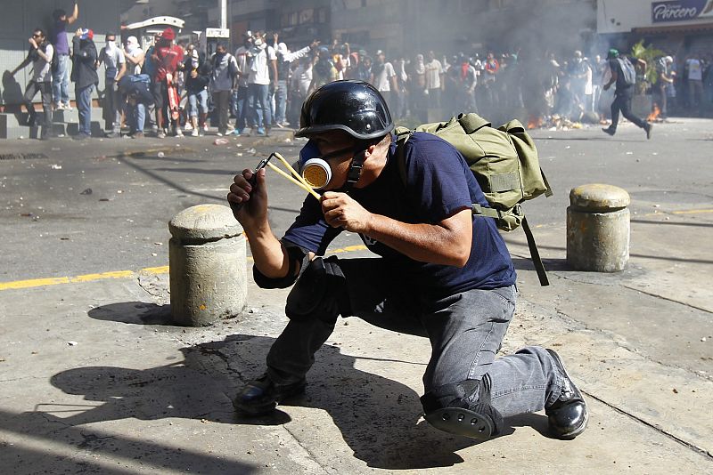 Un manifestante amenaza a la policía con un tirachinas durante las protestas contra el presidente de Venezuela Nicolas Maduro.