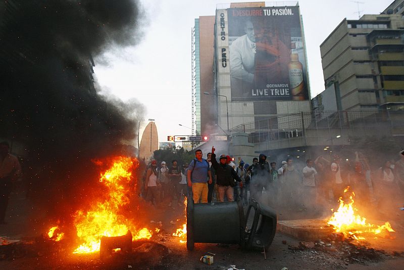 Los manifestantes construyen unca barricada de fuego para mantener la distancia con la policía.