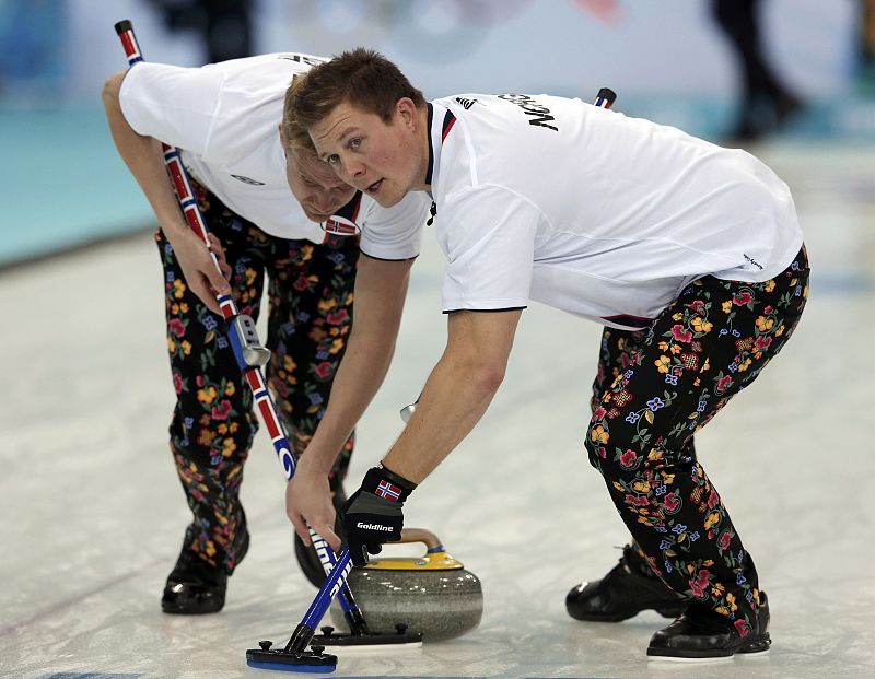 Norway's lead Vad Petersson and second Svae sweep ahead of a stone during their men's curling round robin game against Canada at the 2014 Sochi Winter Olympics