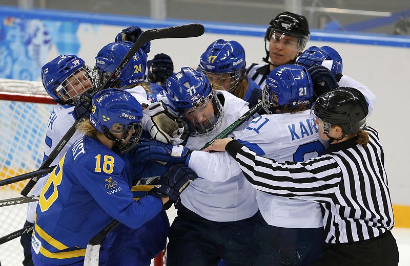 Referee jumps in to break up a scuffle between Sweden and Finland players during the second period of their women's ice hockey playoffs quarter-final game at the Sochi 2014 Winter Olympic Games