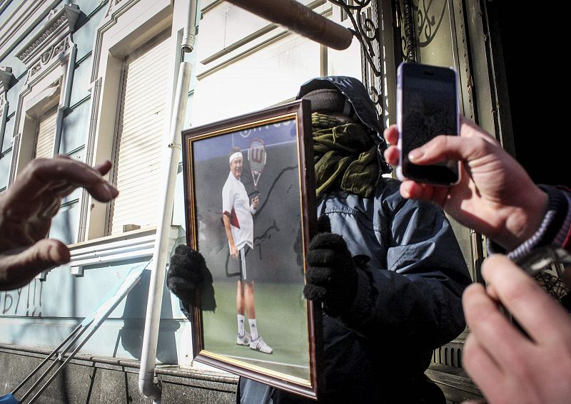 Manifestantes ucranianos con una fotografía de Yanúkovich tras el saqueo de la sede de su partido en Kiev