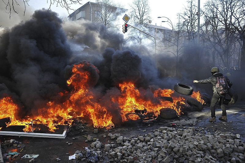 Un manifestante lanza un neumático en una hoguera