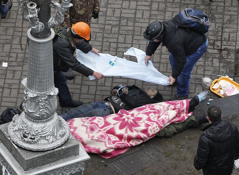 Manifestantes cubren el cadáver de un compañero en la Plaza de la Independencia, junto a otro cuerpo