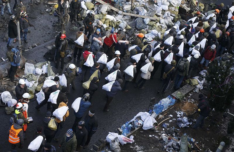 Anti-government protesters carry bags filled with stones to build barricades around the Independence Square during clashes with riot police in Kiev