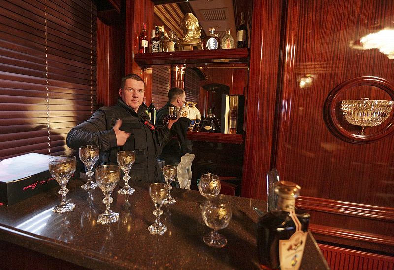 A man gestures behind the interior bar inside the residence as anti-government protesters and journalists walk on the grounds of the Mezhyhirya residence of Ukraine's President Viktor Yanukovich in the village Novi Petrivtsi outside Kiev