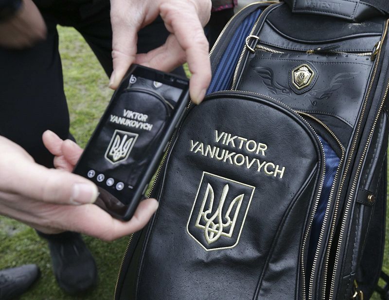 A man takes a picture of a golf bag as anti-government protesters and journalists walk on the grounds of the Mezhyhirya residence of Ukraine's President Viktor Yanukovich in the village Novi Petrivtsi outside Kiev