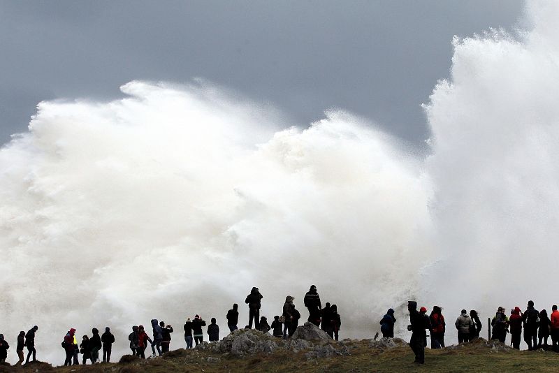 Varias personas observan las grandes olas formadas en el salto de los Bufones de Pria, en Llanes.