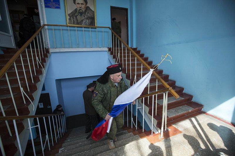 Tras la retirada de los militares ucranianos, un hombre exhibe una bandera rusa.