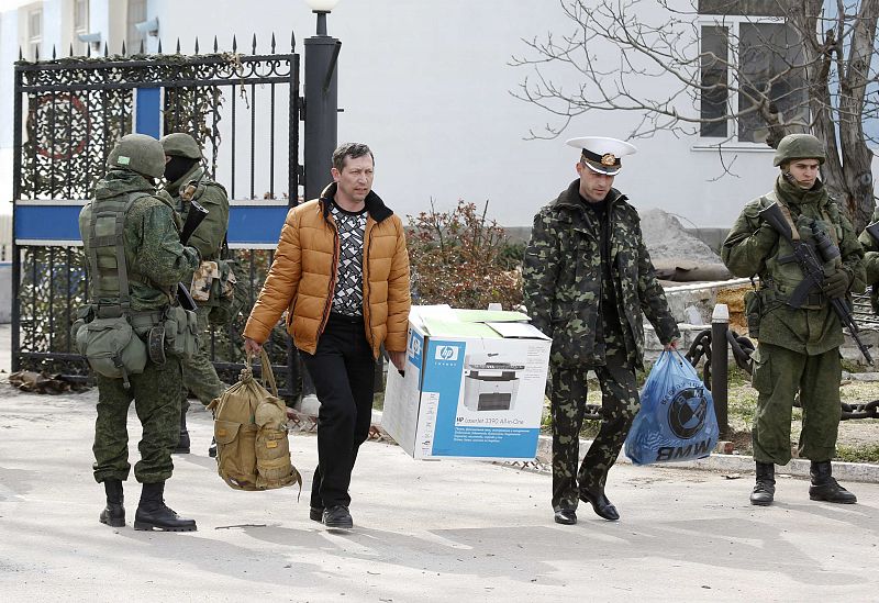 Dos soldados, supuestamente ucranianos, salen de la base con sus pertenencias en una maleta, una caja y una bolsa de plástico.