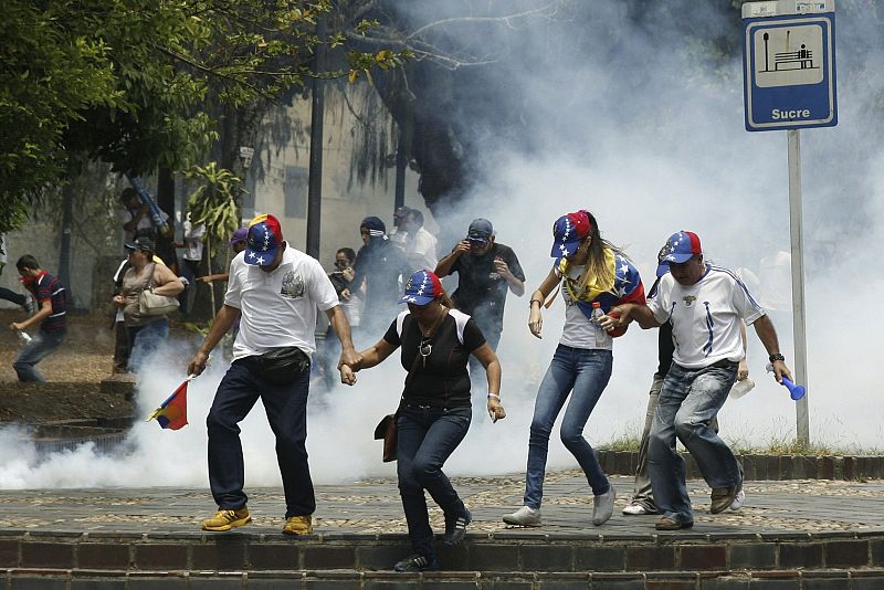 Manifestantes antigubernamentales huyen del gas lacrimógeno lanzado por la policía