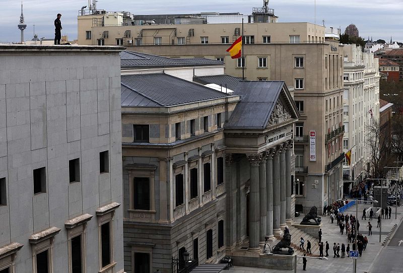 Un agente de policía vigila desde la azotea del Congreso de los Diputados durante la capilla ardiente por Adolfo Suárez