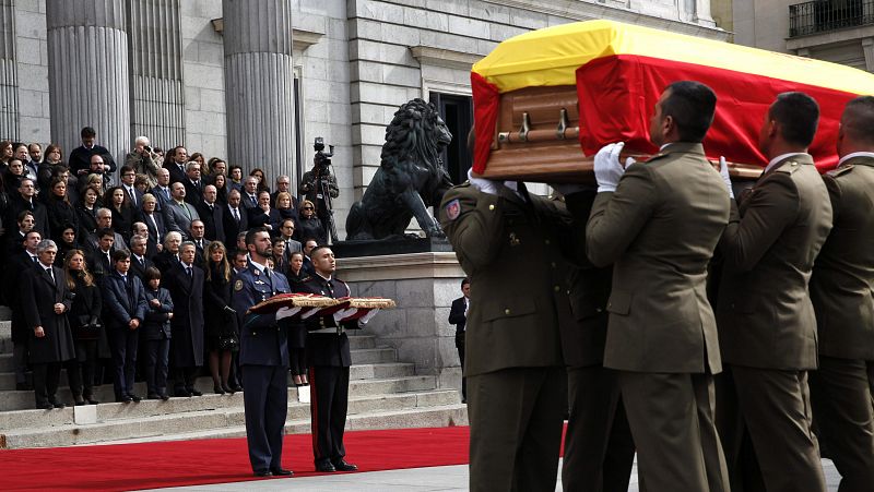 Tras el féretro, un soldado del Ejército del Aire porta el Toisón de Oro que concedió el rey a Suárez y un marinero lleva el Collar de la Real y Distinguida Orden Española de Carlos III, otorgada este lunes a título póstumo.