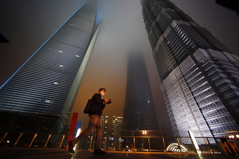 Man walks past skyscrapers Shanghai World Financial Center, Shanghai Tower and Jin Mao Tower at financial district of Pudong during Earth Hour in Shanghai