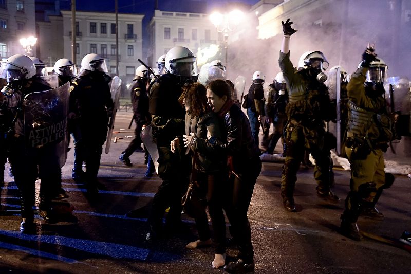 Una manifestante ayuda a una mujer descalza a retirarse tras una carga policial