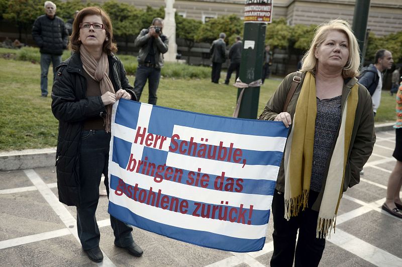 Dos mujeres sostienen una bandera griega en la que se pide al ministro alemán de Finanzas que devuelva lo robado