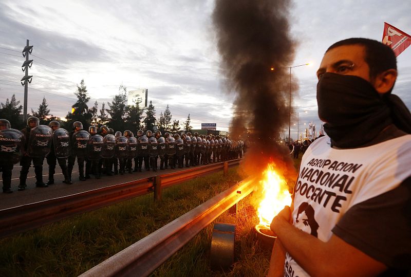 Un manifestante sujeta una bengala frente a los policías durante el bloqueo de una autopista en Buenos Aires
