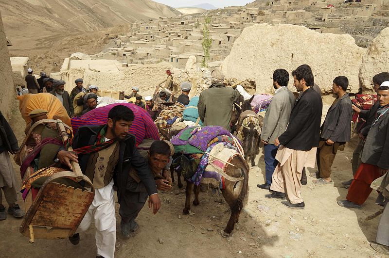 People walk with their belongings near the site of a landslide at Badakhshan province