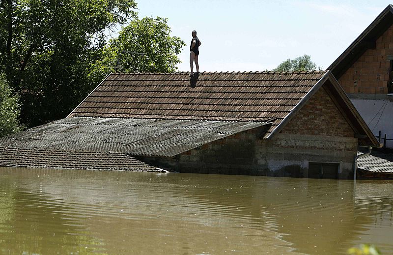 A man waits to be rescued from his house during heavy floods in Vojskova