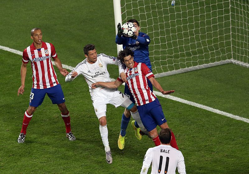 El portero del Atlético de Madrid, Thibaut Courtois, bloca un balón aéreo por encima de Tiago y Cristiano Ronaldo