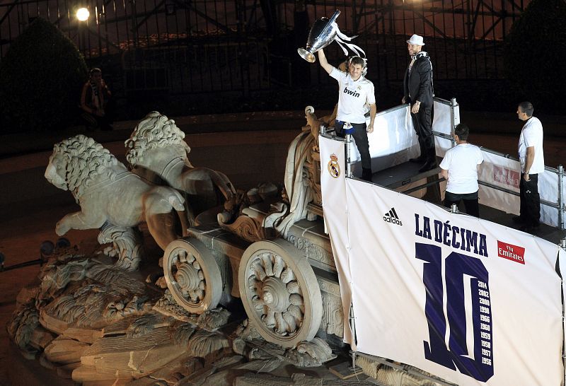 Los capitanes del Real Madrid Iker Casillas y Sergio Ramos ofrecen la copa a los aficionados junto a la estatua de la Cibeles