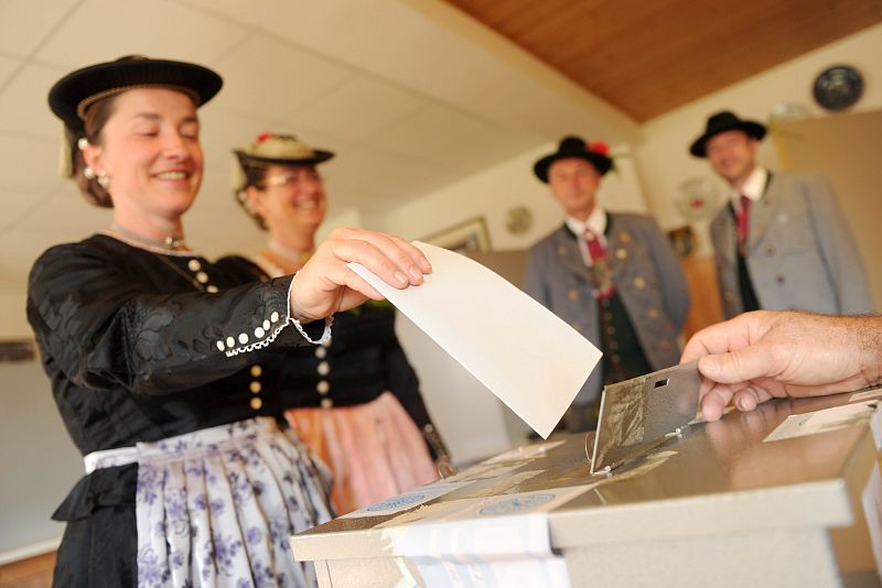 Un grupo de votantes vestido con atuendo bávaro deposita su voto para las elecciones europeas en un colegio electoral en Deining, Baviera (Alemania).