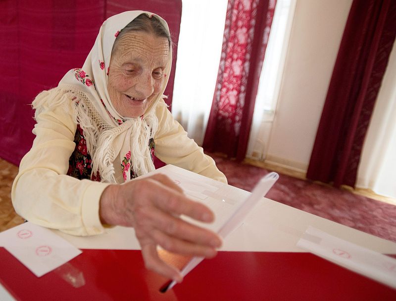 Una mujer polaca de 91 años introduce su voto en un colegio electoral en Lodz, (Polonia).