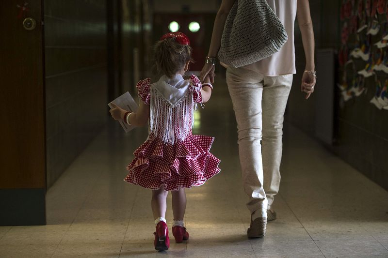 Una madre con su hija vestida de flamenca coincidiendo con la feria de Córdoba, en un colegio electoral.