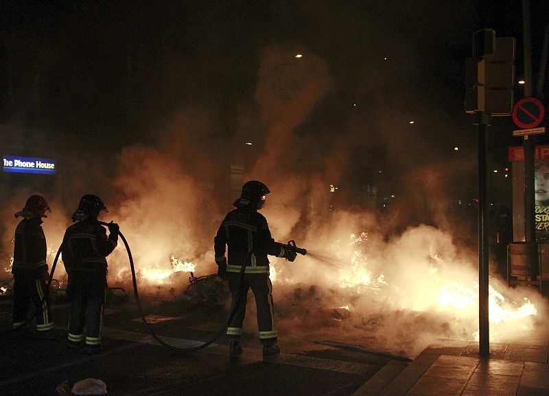 bomberos apagan el fuego durante los incidentes violentos en el barrio de Sants