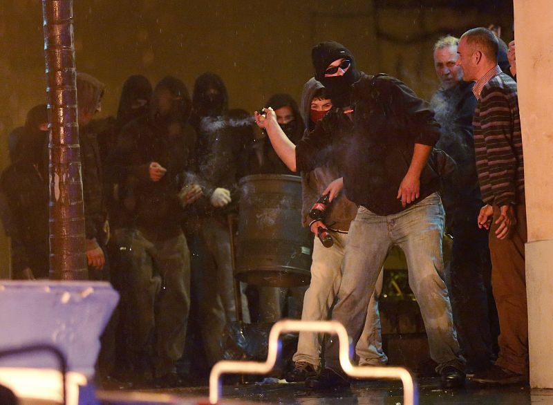 Un hombre arroja un petardo durante los disturbios