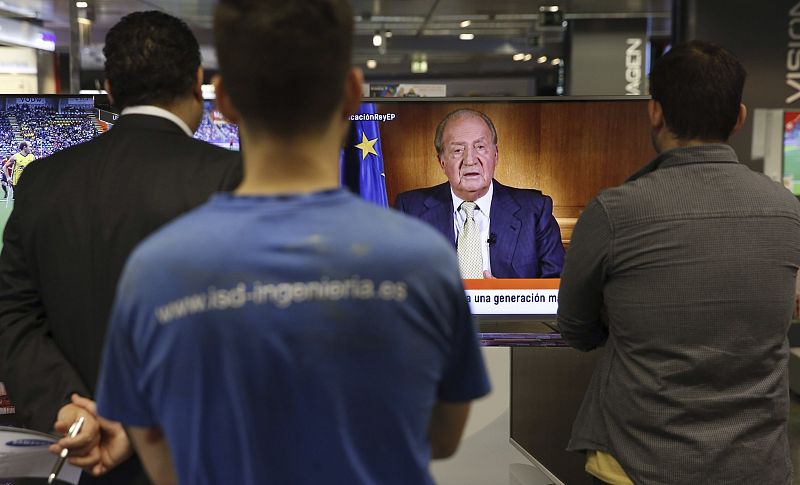 Varias personas escuchan al rey don Juan Carlos en un centro comercial