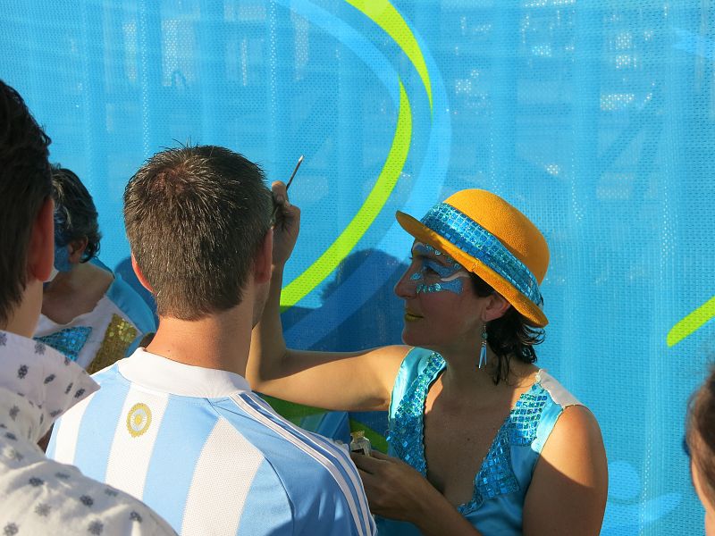 Una aficionada pinta la cara a los seguidores con la bandera argentina.