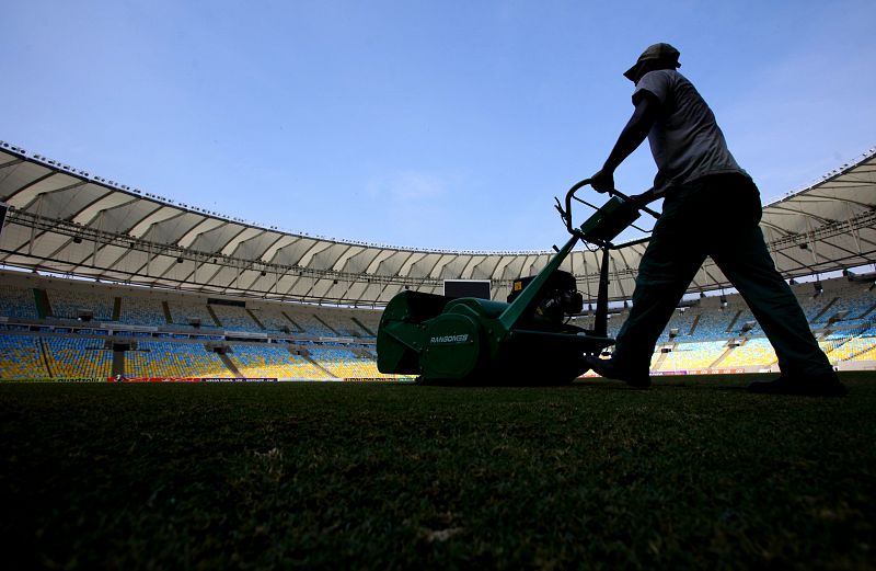 Un operario corta el césped del estadio.