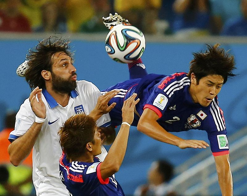 El lateral japonés Atsuto Uchida (derecha) salta por encima del jugador griego Giorgios Samaras (izquierda)