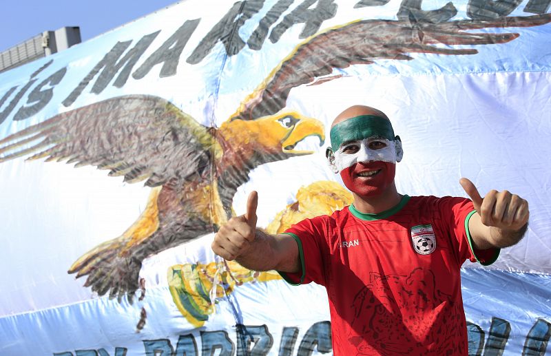 Un hincha iraní posa delante de una bandera argentina