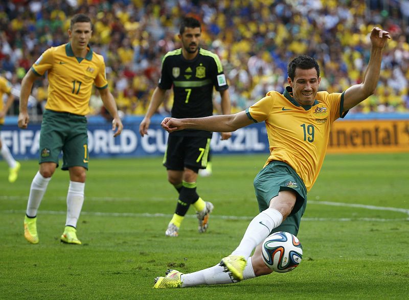 El jugador australiano Ryan McGowan golpea el balón ante la mirada de David Villa.