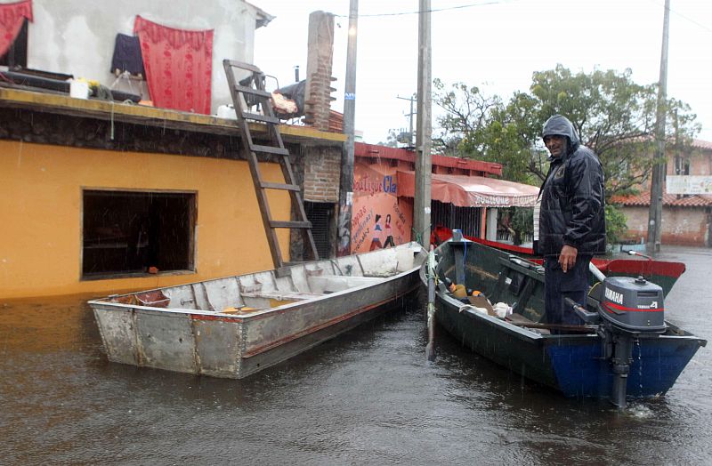 Un hombre permanece en una balsa en una calle inundada en un barrio de Asunción.