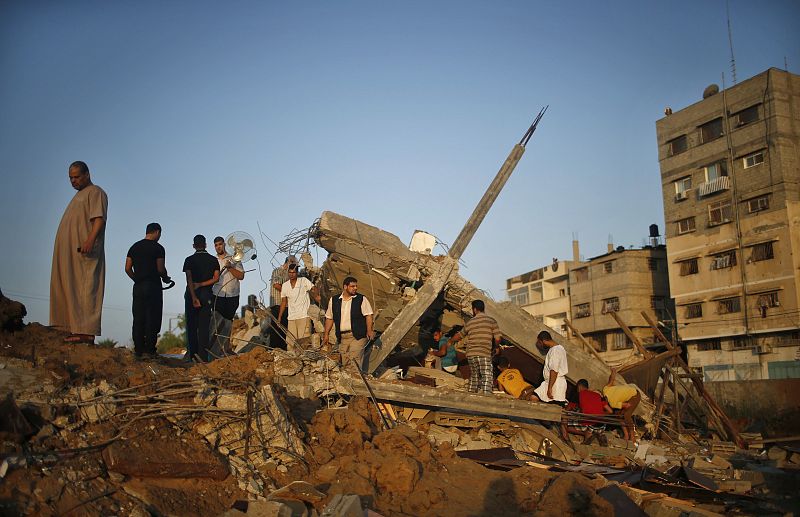 Un grupo de palestinos sobre los escombros de una casa destruida durante el ataque aéreo de Israel sobre la ciudad de Gaza.